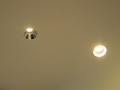 左が「LEDグレアユニバーサルダウンライト」、右が従来の照明。従来照明は反射光で天井を明るく照らす。直視すると眩しいくらいだ。「LEDグレアユニバーサルダウンライト」は反射せず、真下のみを明るく照らす。